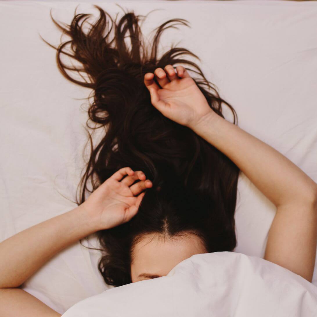 Vrouw heeft slaap nodig en ligt met hoofd onder de dekens