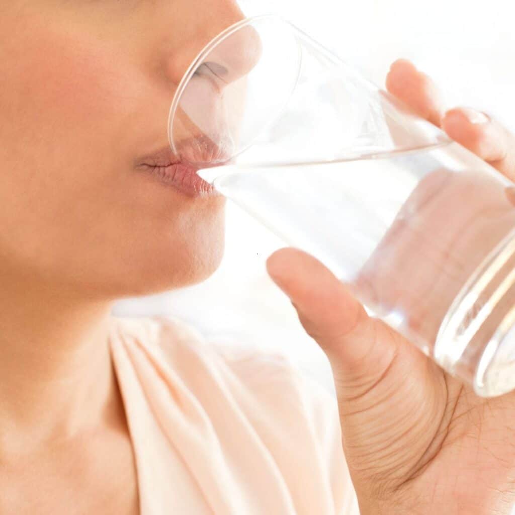 Vrouw hydrateert genoeg voor het slapen gaan, hydratatie belangrijk voor slaapkwaliteit