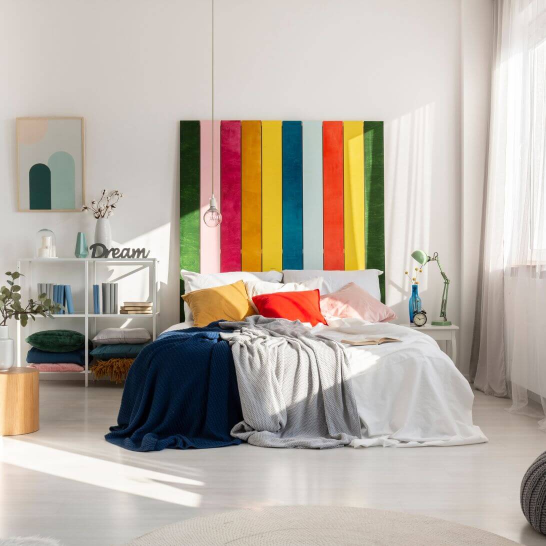 Slaapkamer met bed en regenboogschilderij