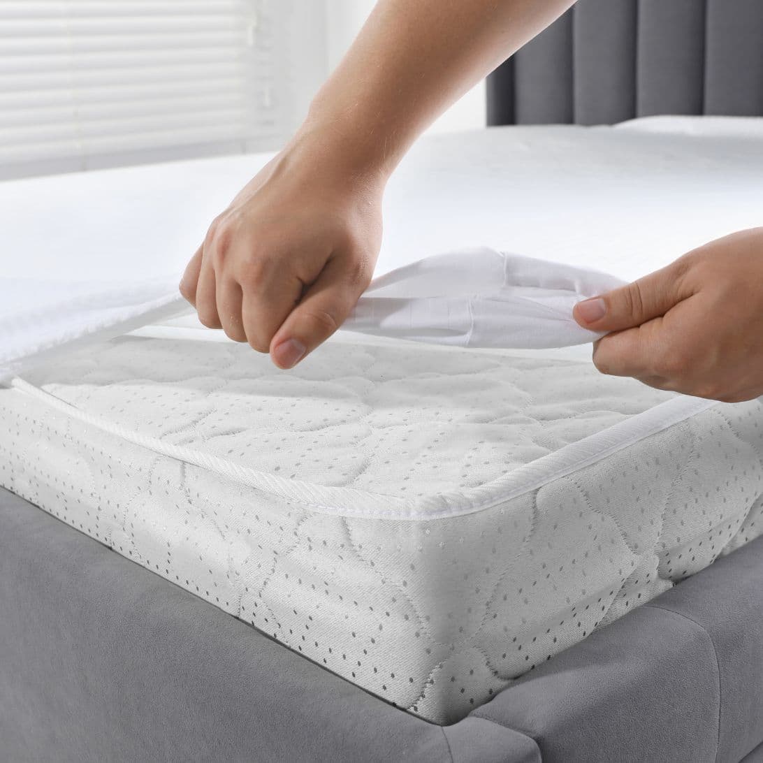 Handen trekken matrasbeschermer over matras