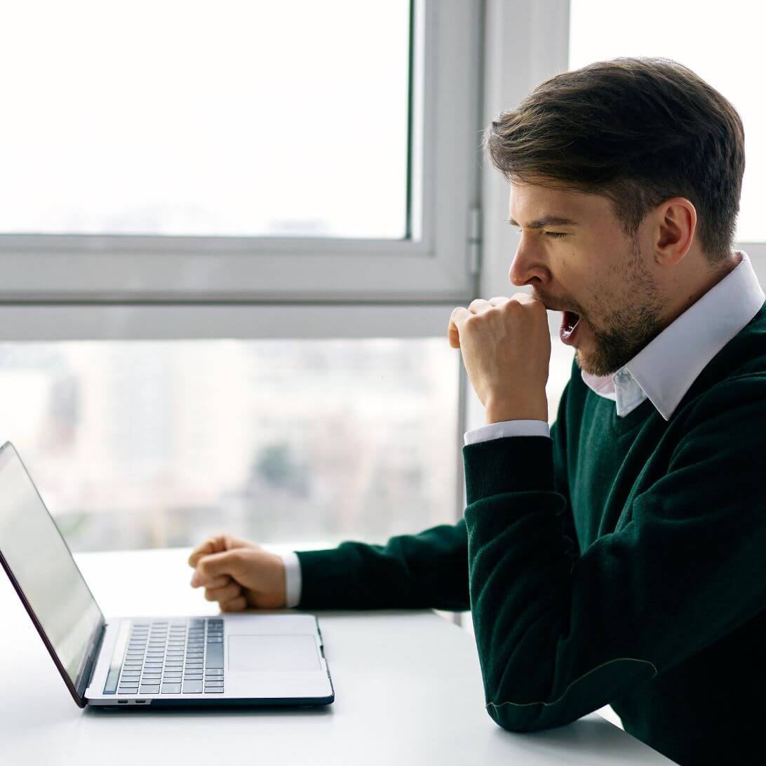 Man met slaap en gapend op werk, voor een laptop