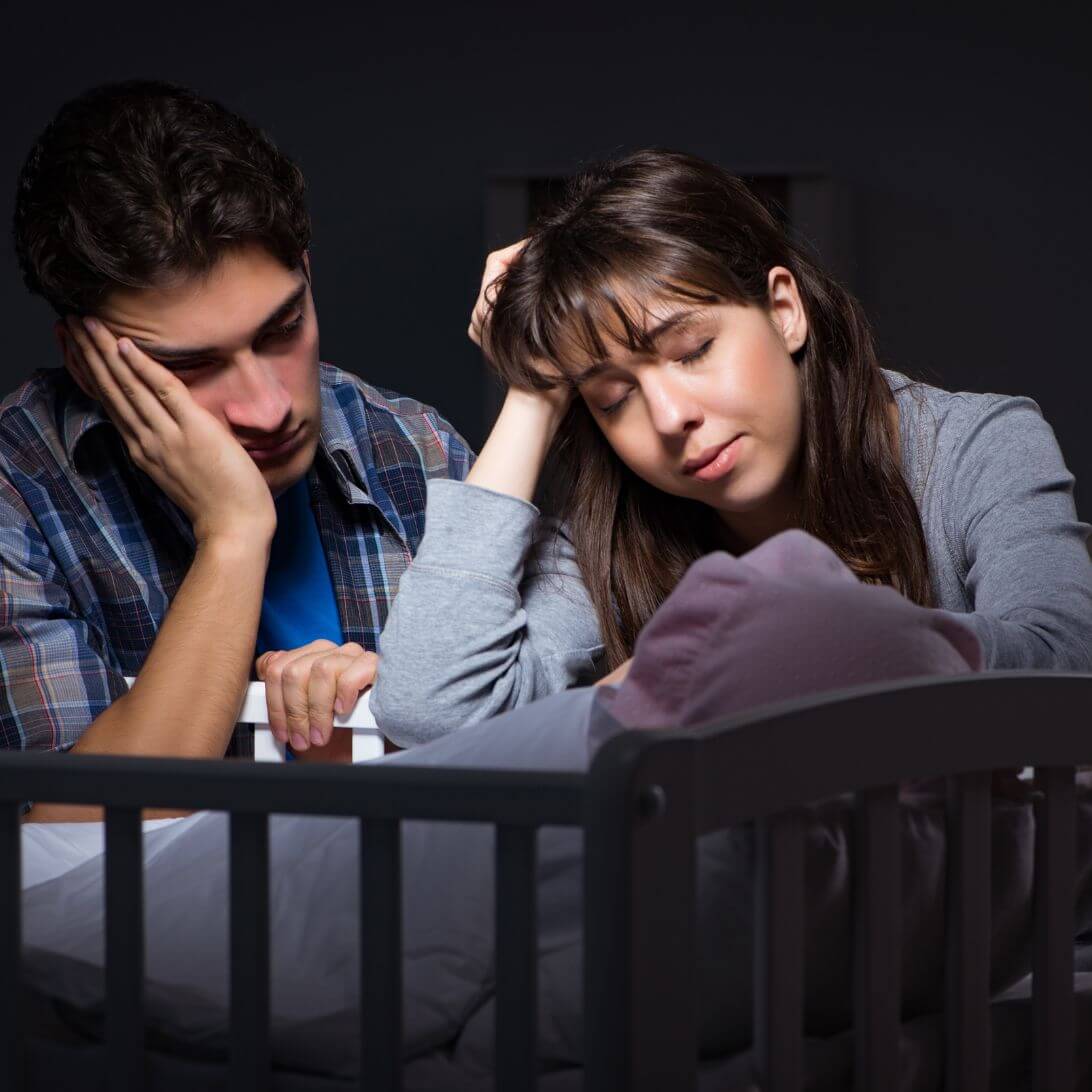 Nieuwe ouders met slaapproblemen, naast wiegje