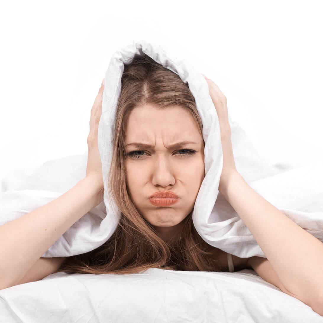 Vrouw heeft last van ochtendhumeur, ligt met deken over hoofd in bed