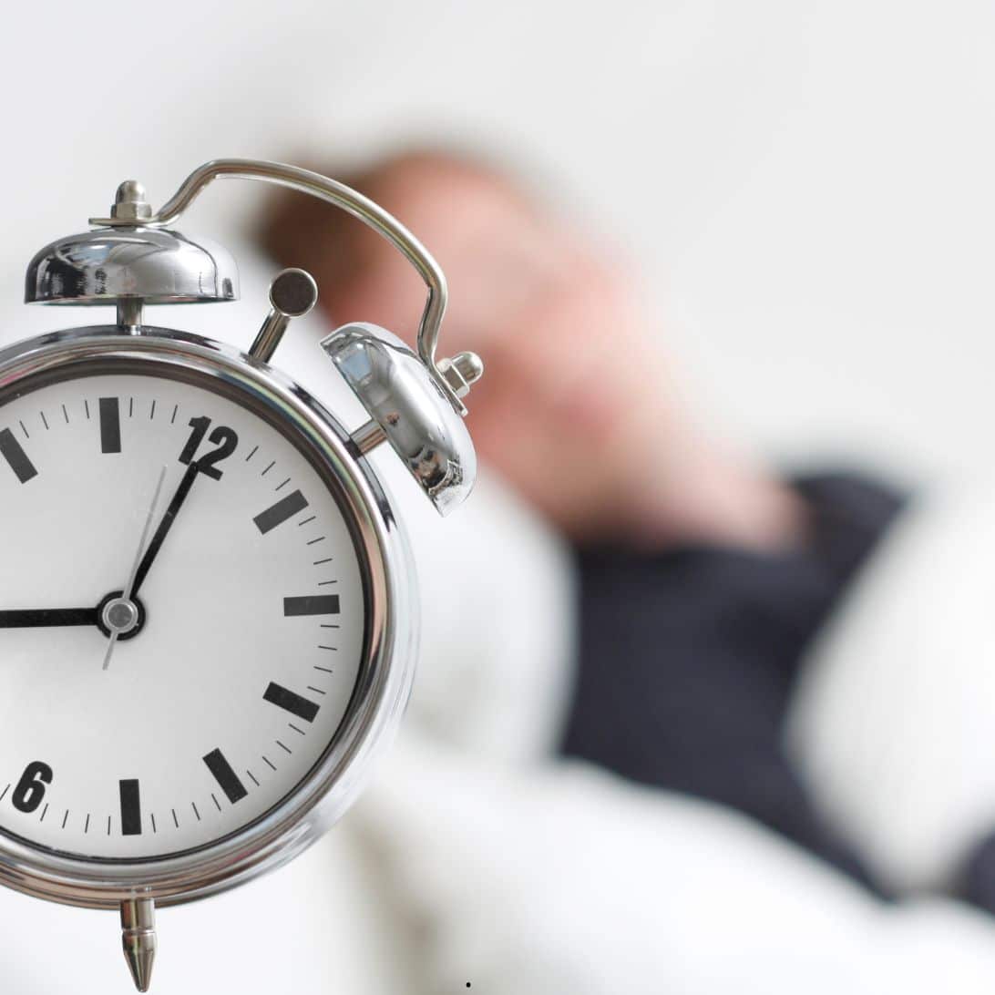 Wekker met een slapende persoon die genoeg slaapt voor een gezonde slaapduur
