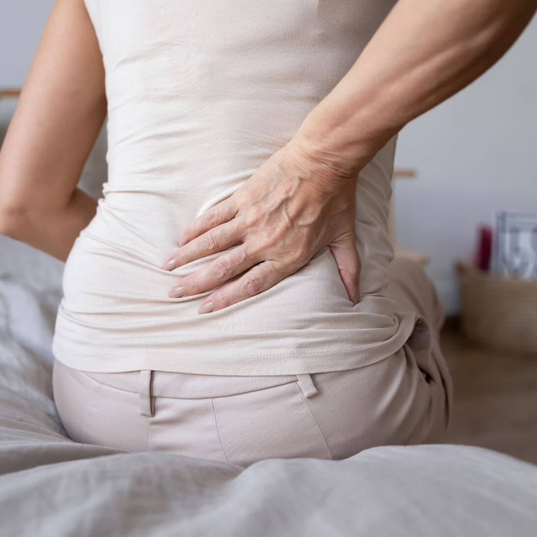 Vrouw met rugklachten zittend op bed
