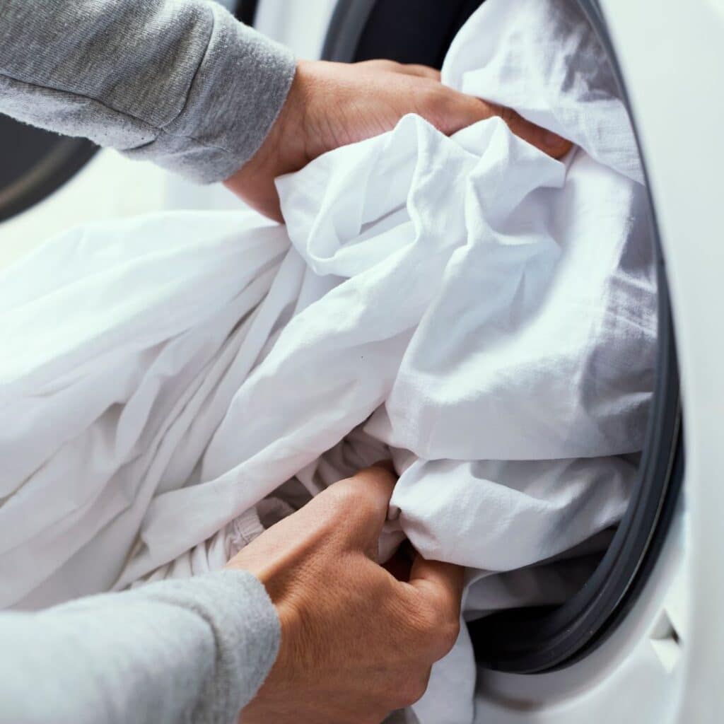 Beddengoed wordt in schone wasmachine gestopt