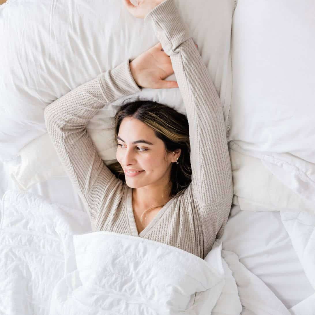 Vrouw rekt zich uit na goede nachtrust, toont belang van slaap