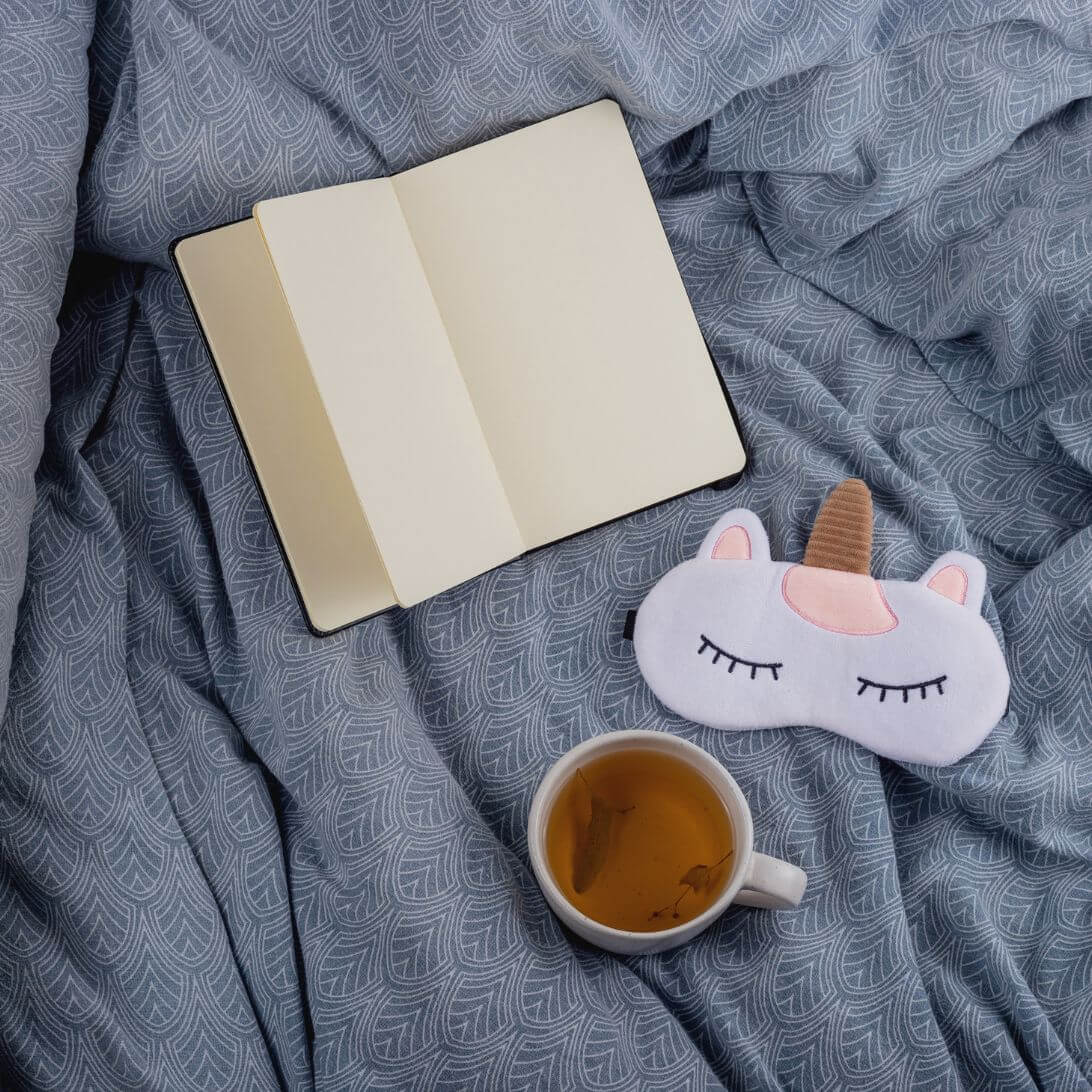Slaapdagboek, slaapmasker en thee op bed