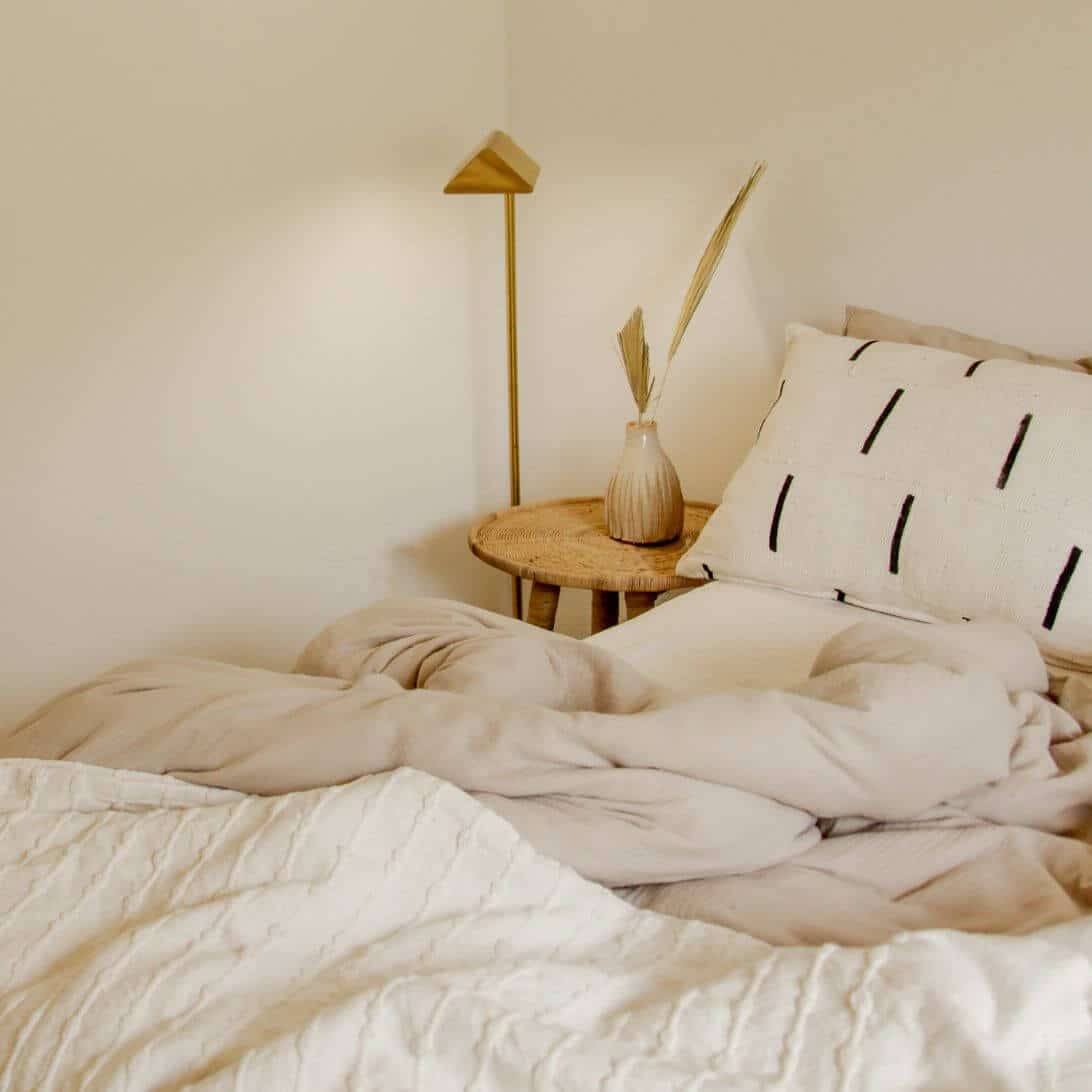 Slaapomgeving met bed, dekens, kussens en nachtkastje
