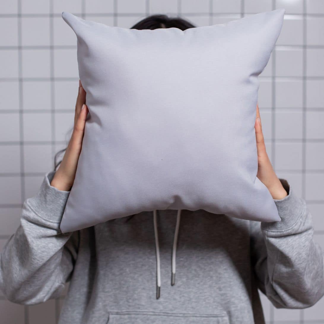 Vrouw houdt kussen voor haar gezicht: Welk Tempur kussen is de beste voor u?