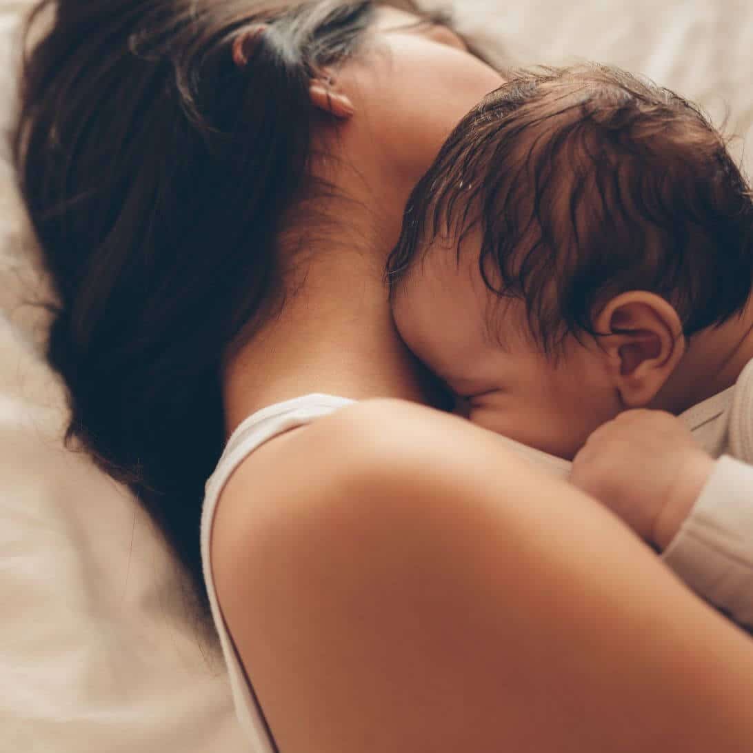 Moeder slaapt samen met baby in bed