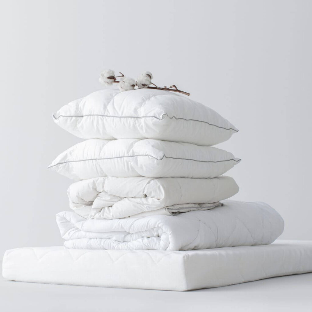 Stapel met Hema beddengoed, met onder andere een molton, dekbed en kussens