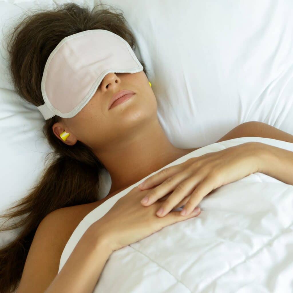 Vrouw slaapt met slaapmasker en slaapoordoppen in