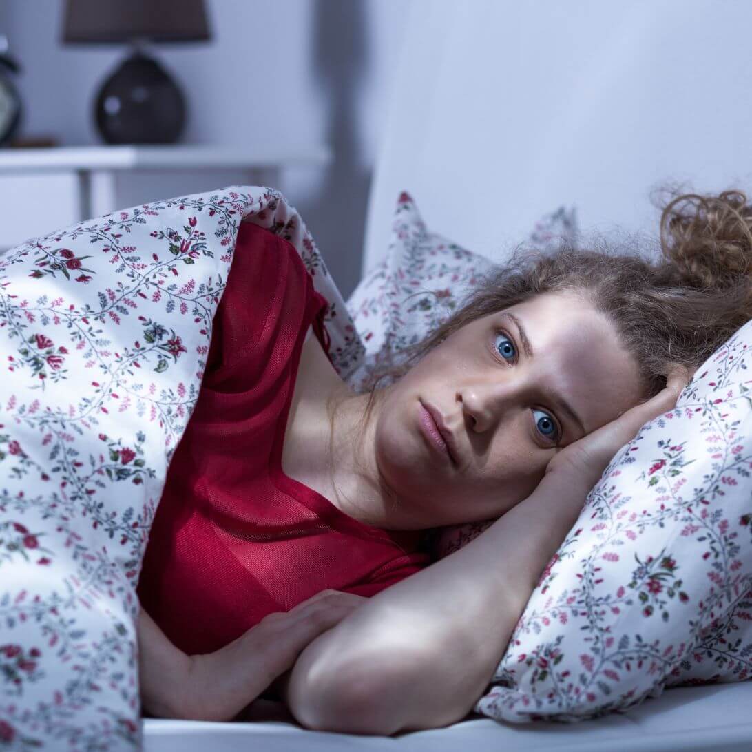 Vrouw ligt wakker in bed en heeft last van slaapproblemen